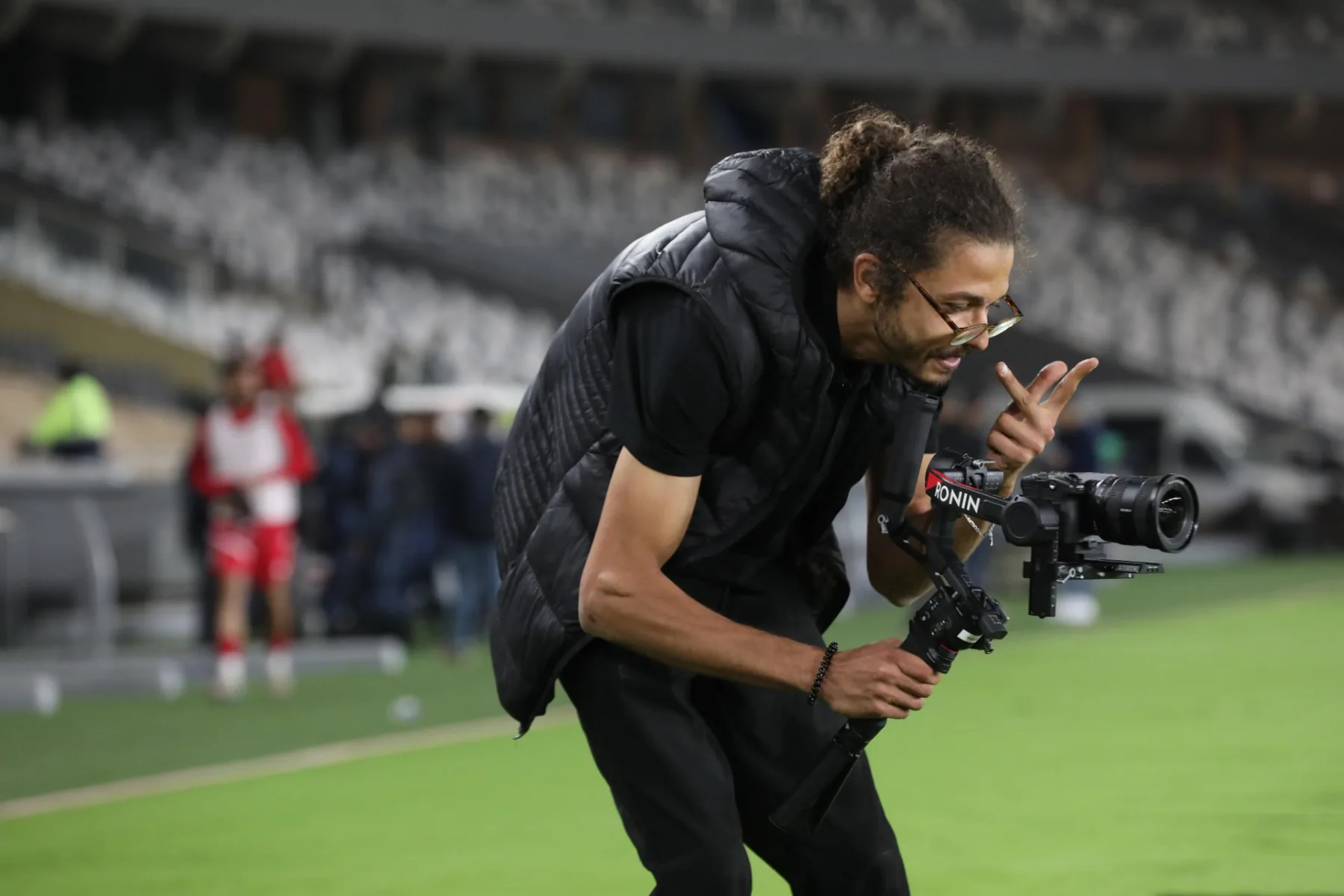 Asaad crouched pitchside operating a gimbal-mounted camera during a live match