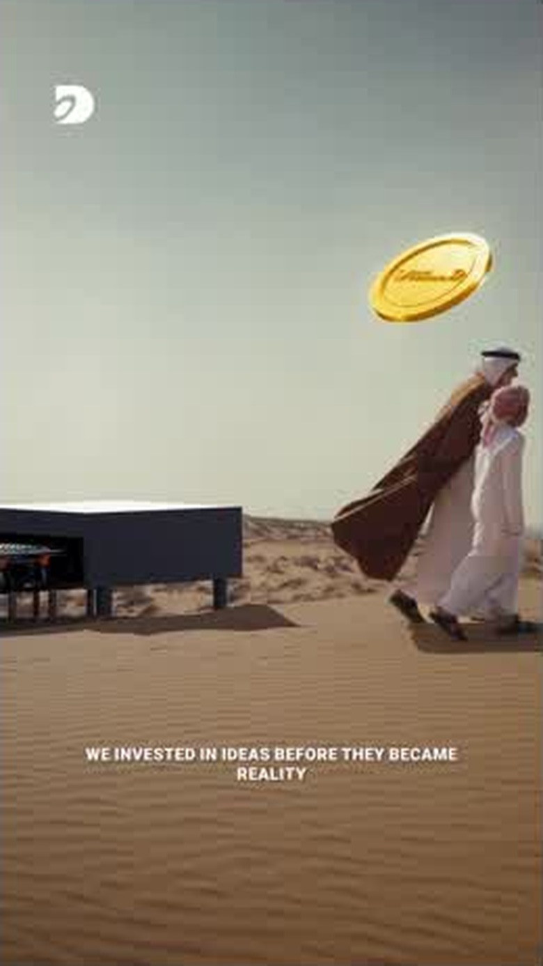 A symbolic gold coin suspended above the sand beside the two figures