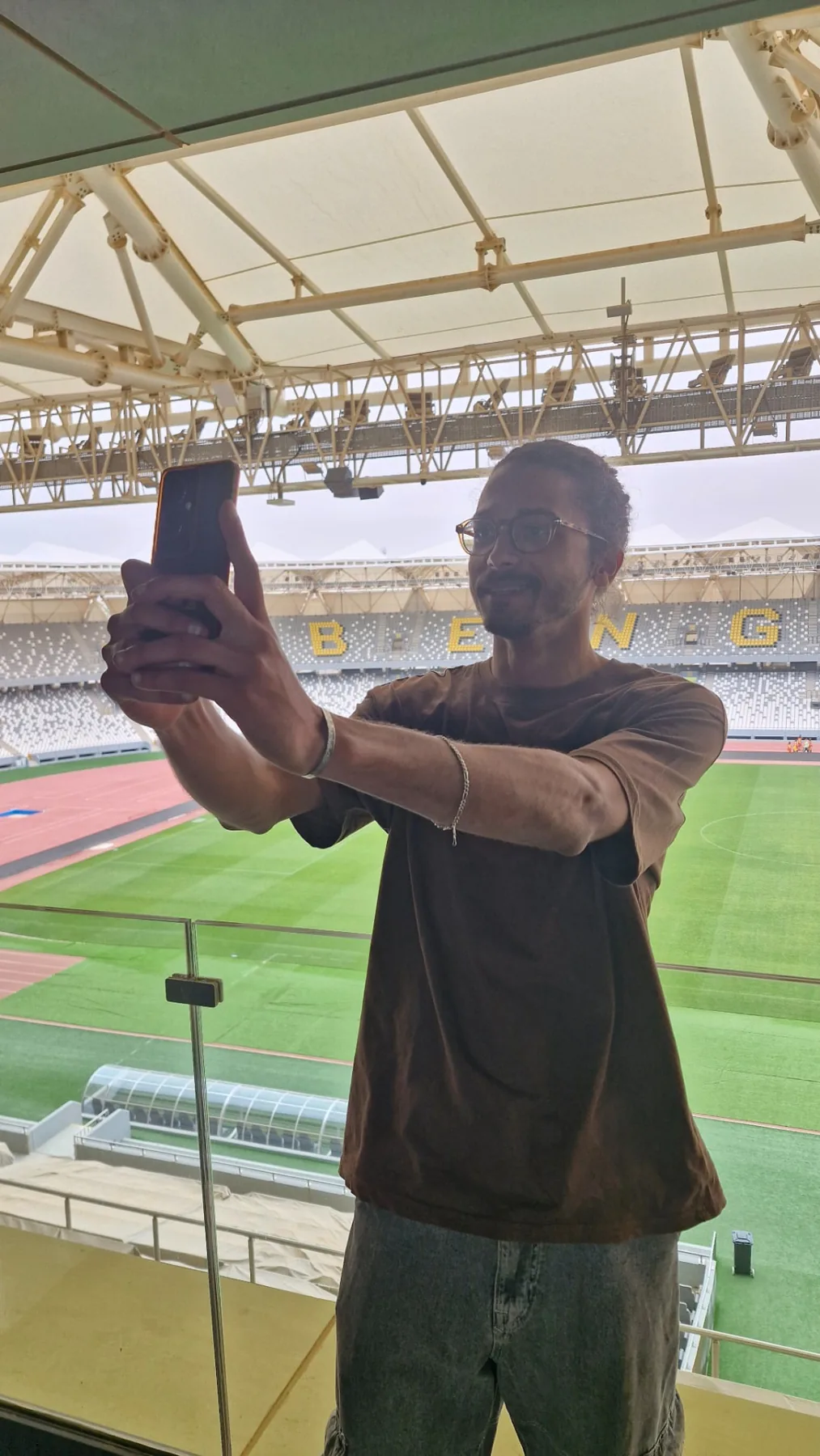Asaad filming on his phone from a stadium balcony in the afternoon, off duty