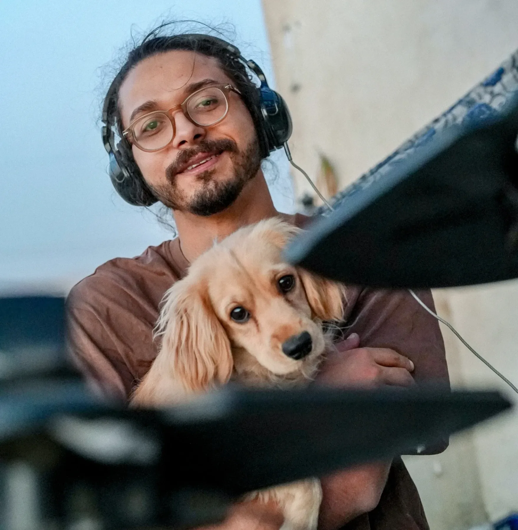 Asaad wearing headphones at a mixing desk, holding his cocker spaniel Gambry close
