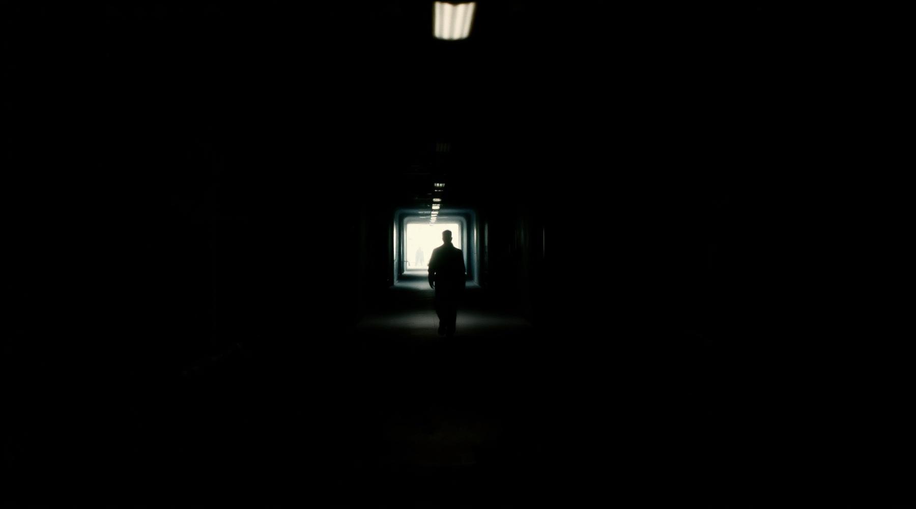 A figure crossing a dark tunnel